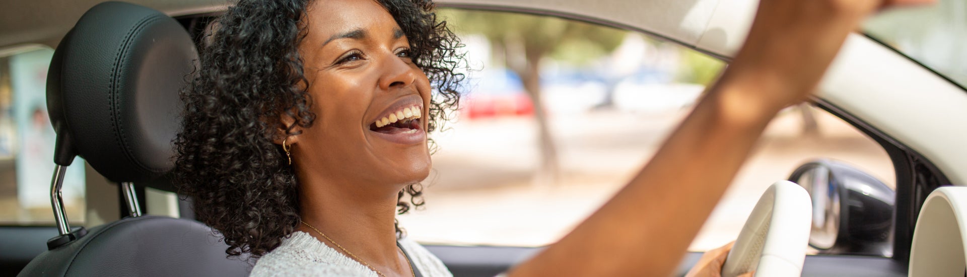 Lady looking at rear-view mirror as she drives off in her new Cadillac
